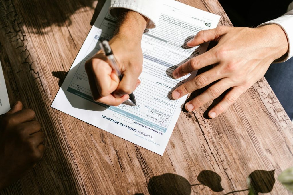 A person reviewing loan documents on a laptop with a cup of coffee.